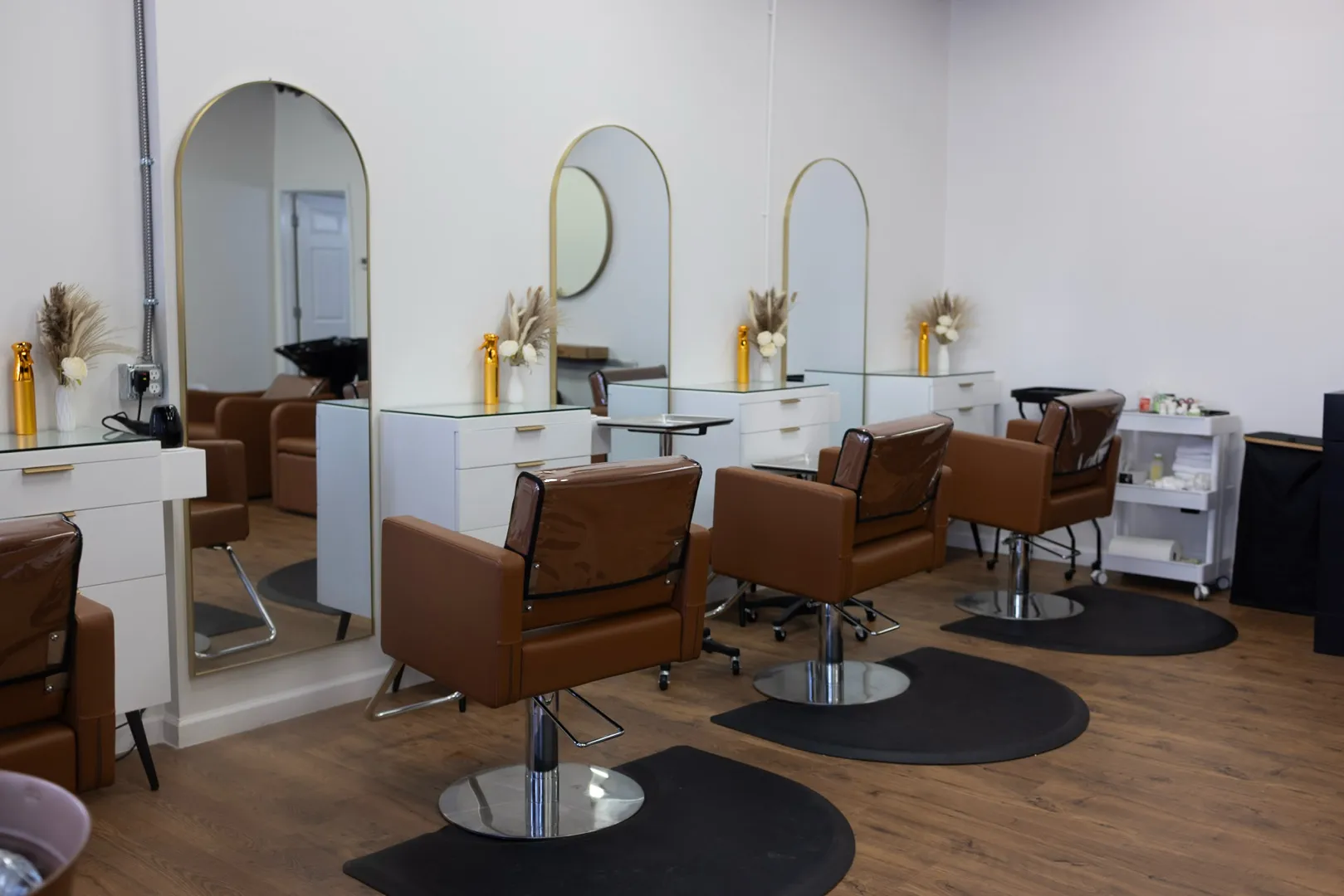 Inside Yours Truly Hair Salon, gold-trimmed arched mirrors, cognac leather chairs and warm wood floors on East Brainerd Road